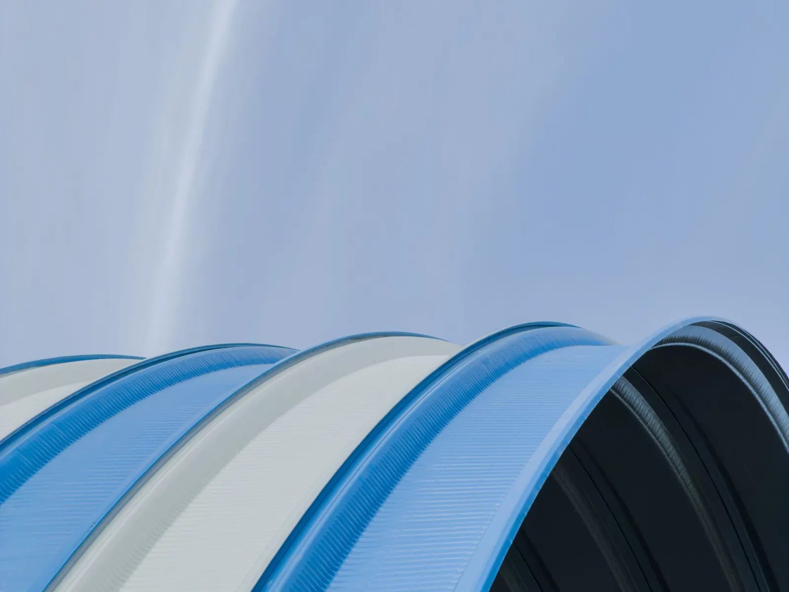 Curved metal roof sheets against a clear sky