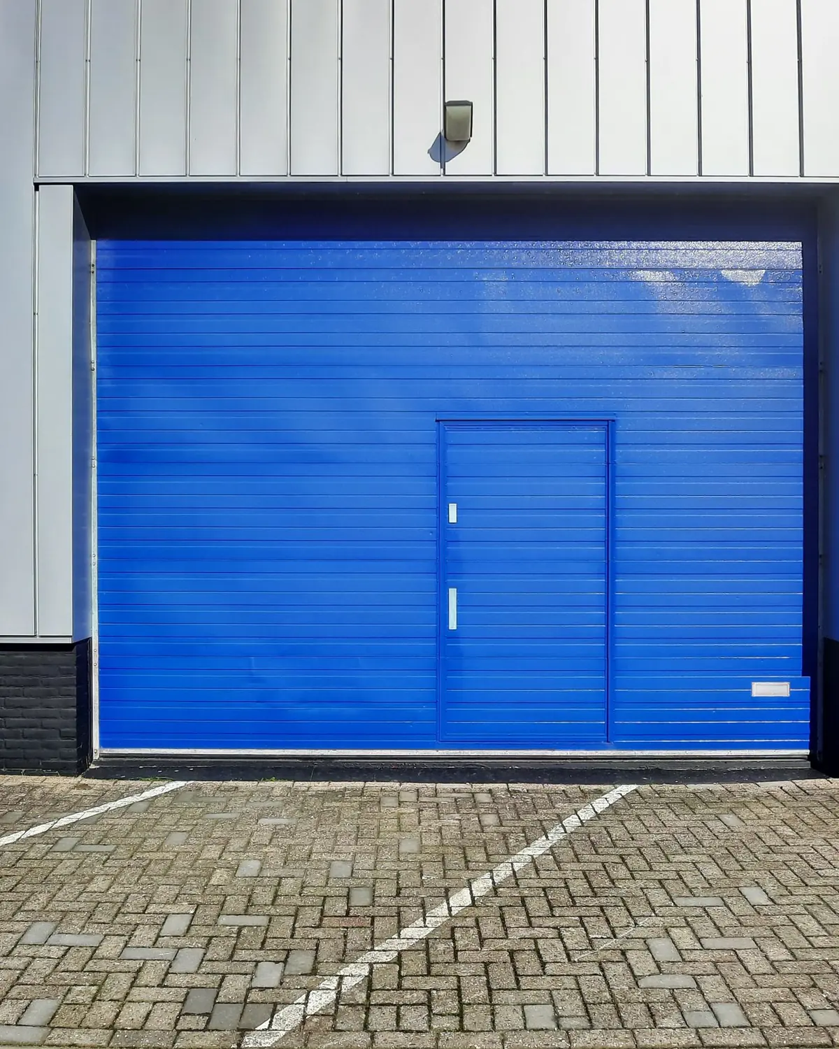Sectional door with a wicket set into a panel-clad wall
