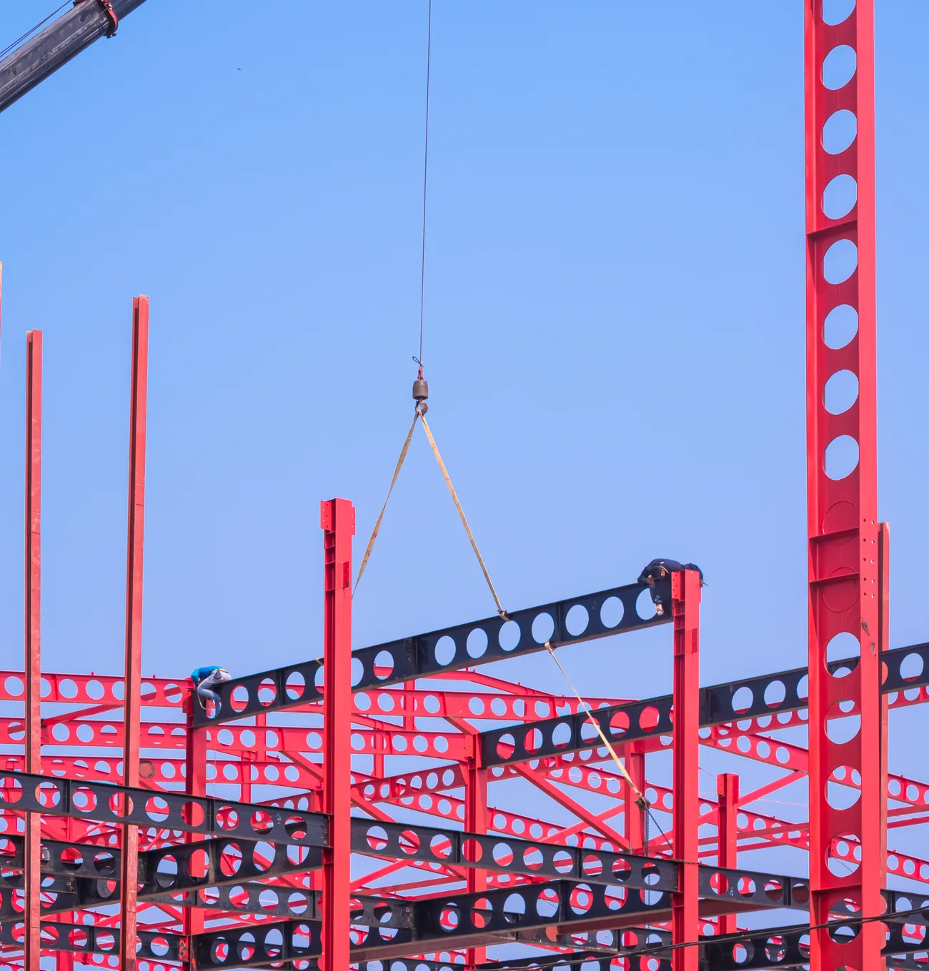 Crane lifting a castellated steel beam into a pre-engineered frame