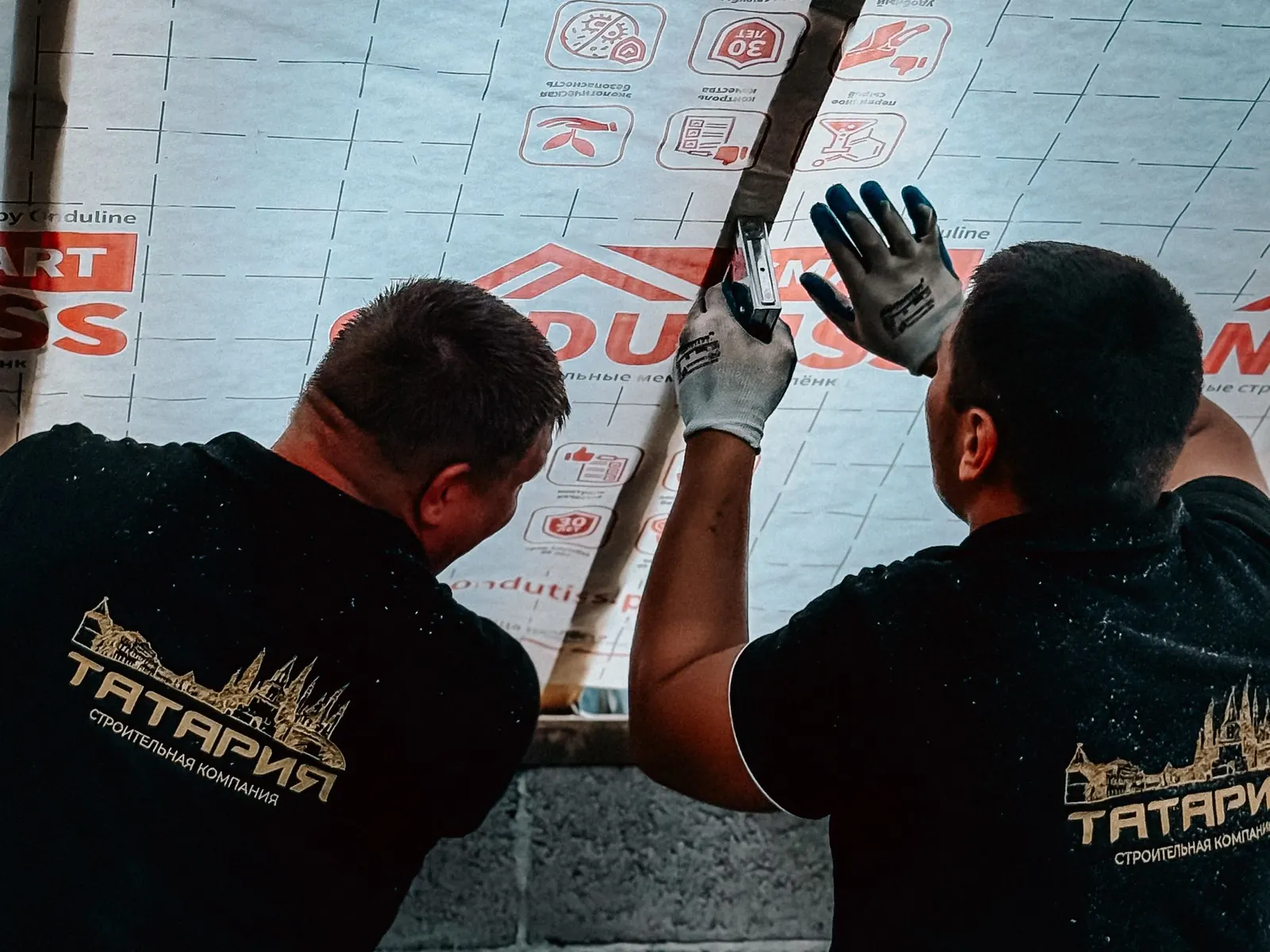 Installers positioning a mineral wool insulation panel